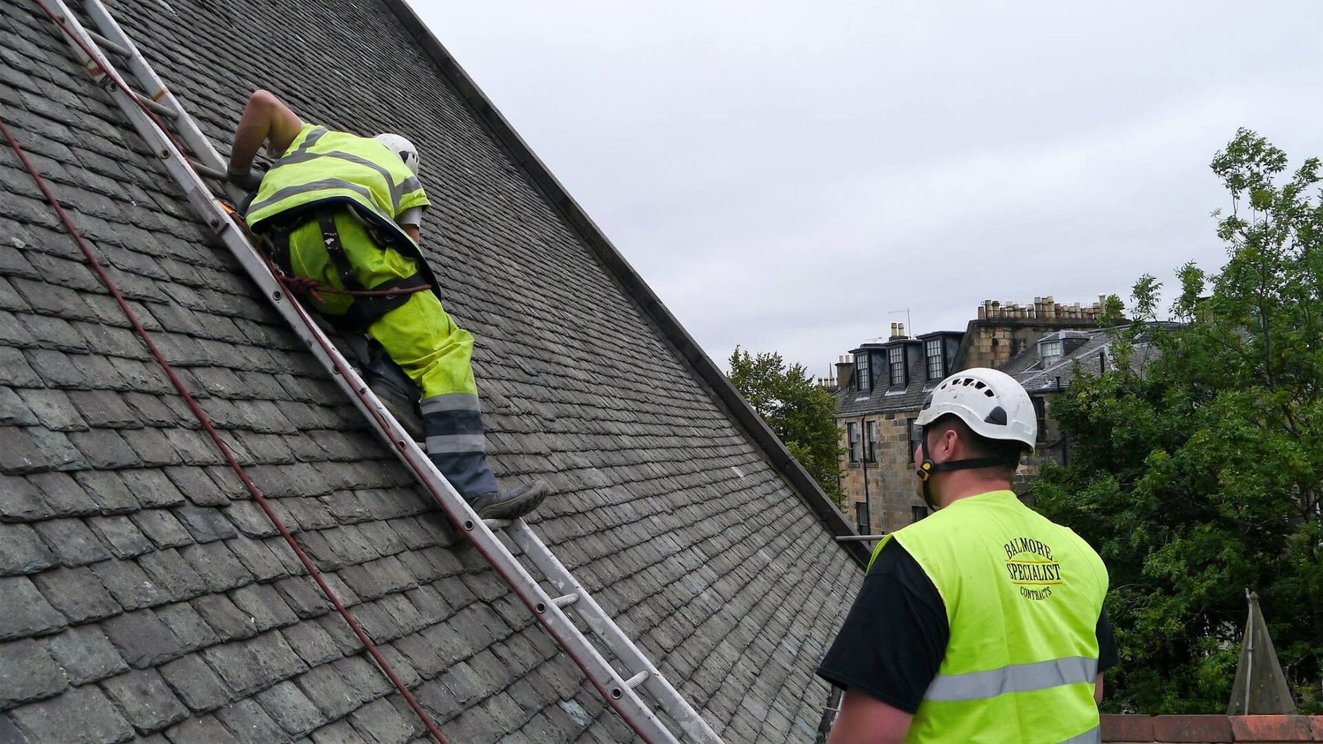 Roofers actively working on UK slate roof in Scotland