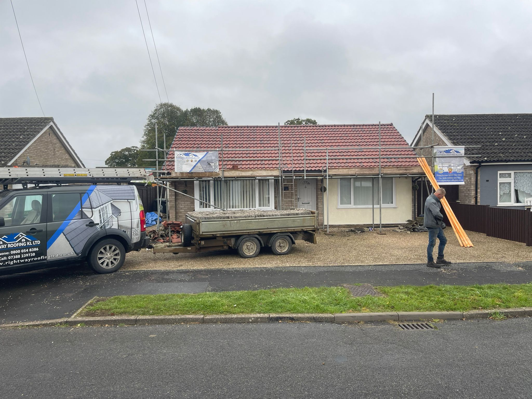 Company van, worker and roofing materials at job site
