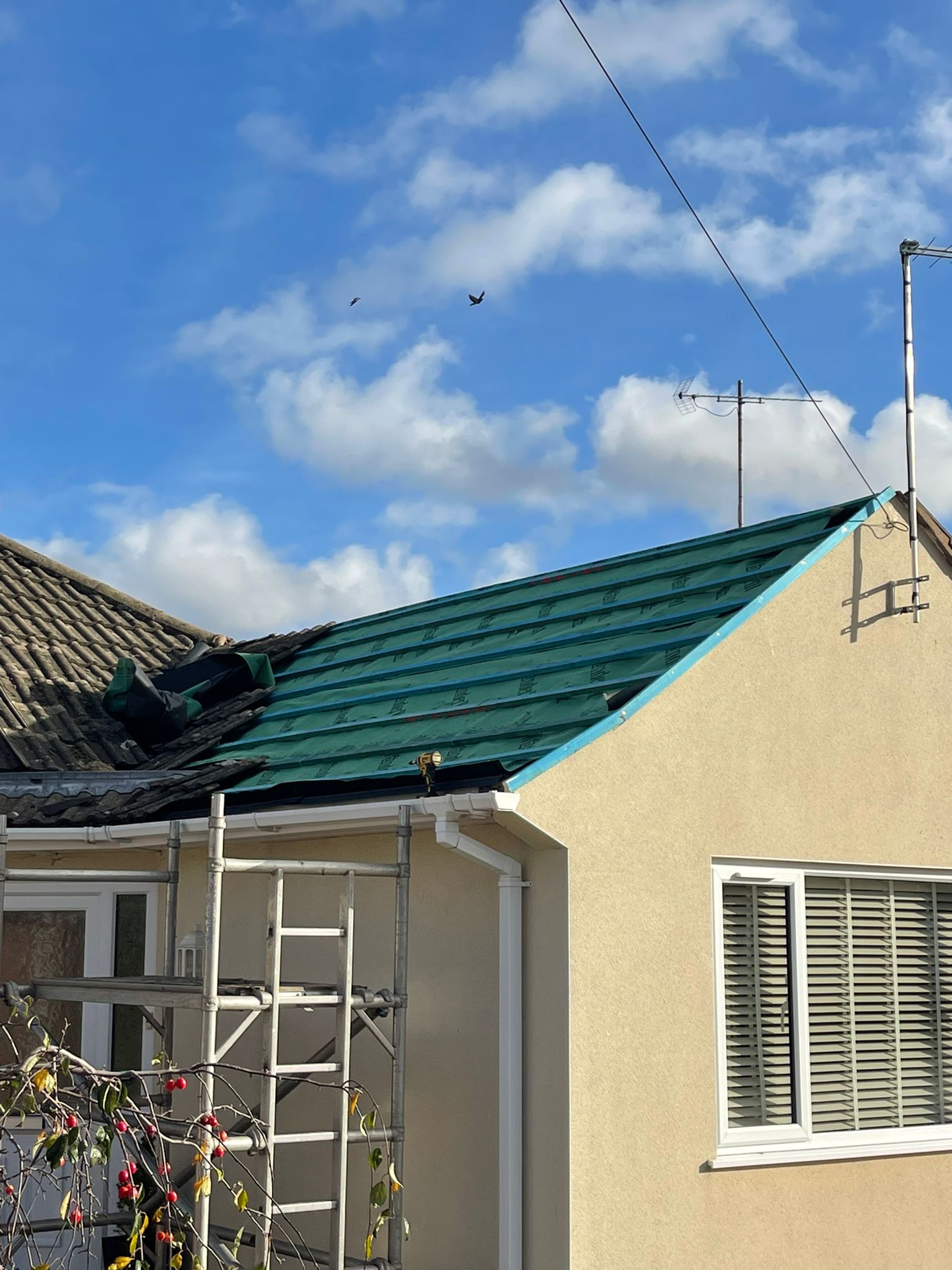 Roofer installing blue membrane underlayment on residential roof